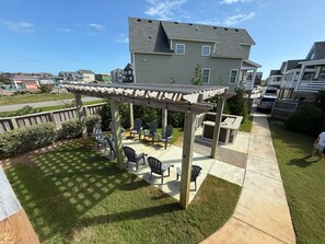 Un quartier résidentiel doté d’un espace patio aménagé avec du mobilier d’extérieur et une pergola.