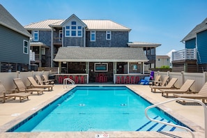 A swimming pool with lounge chairs and a bar area. - Currituck Cottage: Semi-Oceanfront, Private Hot Tub, Community Pool Access! (Nags Head)