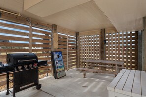 An outdoor patio area with a grill, a bench, and a wooden fence. - Currituck Cottage: Semi-Oceanfront, Private Hot Tub, Community Pool Access! (Nags Head)