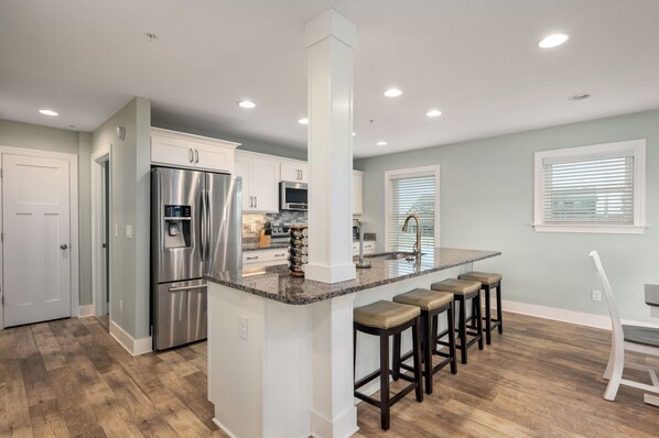 A modern kitchen with a stainless steel refrigerator, a built-in oven, and a granite countertop.