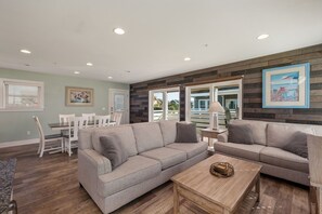 A modern living room with a sectional sofa, a coffee table, and a dining area with a table and chairs.