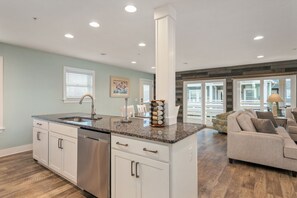 A modern kitchen with a central island, stainless steel appliances, and a dining area with a sofa and table.