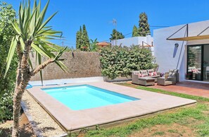 A swimming pool with a patio area, outdoor furniture, and a hedge. - Villa Isla Papua in Chiclana (Chiclana de la Frontera)