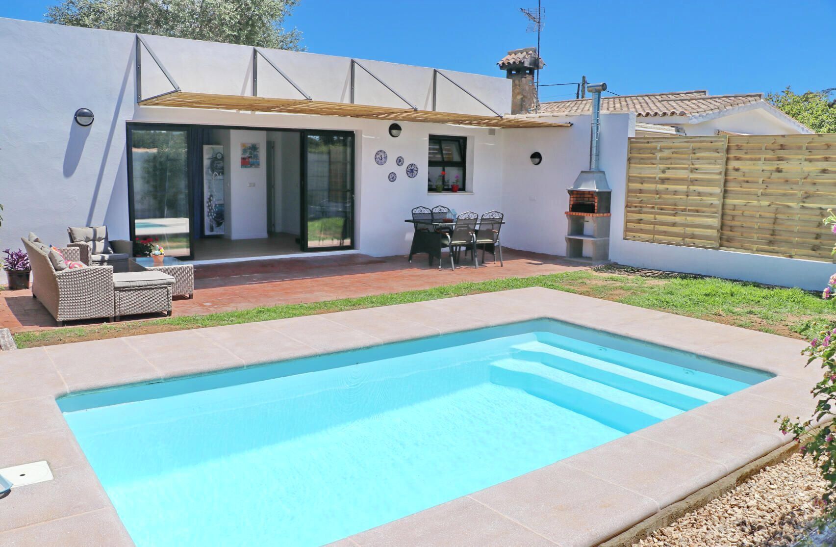 Ein modernes Haus mit Swimmingpool, Gartenmöbeln und einer Terrassenfläche.