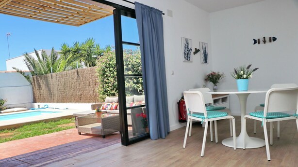 Une pièce avec une piscine, un espace salon extérieur, une table avec des chaises et un extincteur.