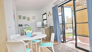 Une cuisine moderne avec une horloge, une table à manger avec des chaises et une vue sur l’espace extérieur.