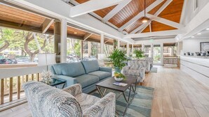 A spacious indoor area with a high ceiling, wooden beams, and large windows.