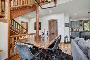 A wooden dining table with two chairs, a staircase, a kitchen, and a living area with a gray sofa. - Snowshoe Circle on Peak 7 | Views, Private Hot Tub, & Great Location! (Breckenridge)