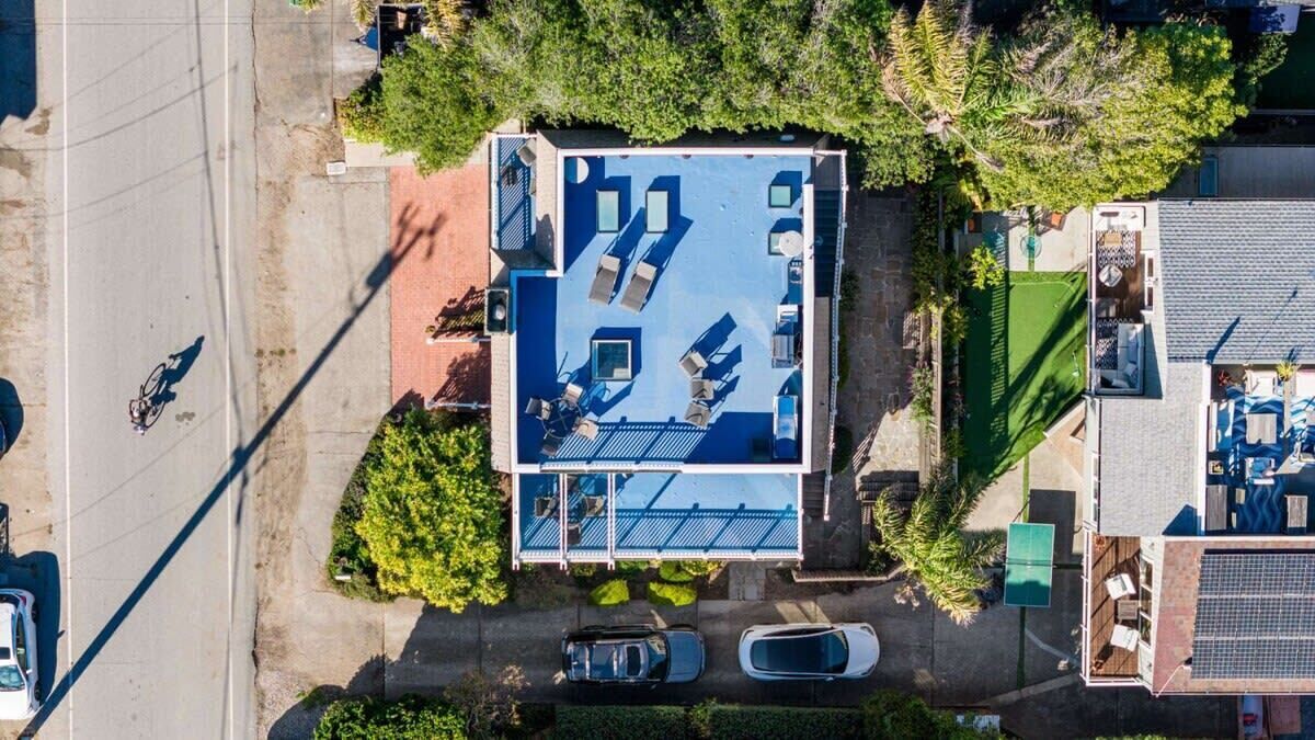 An aerial view of a property with a rooftop deck, a swimming pool, and a covered outdoor area.