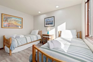 A hotel room with two single beds, a small table with a lamp, and two framed pictures on the wall. - Harbor Home - 2 blocks from the beach! (Santa Cruz)