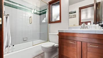 Ein Badezimmer mit einer Duschkabine aus Glas, einer Toilette und Holzschränken.
