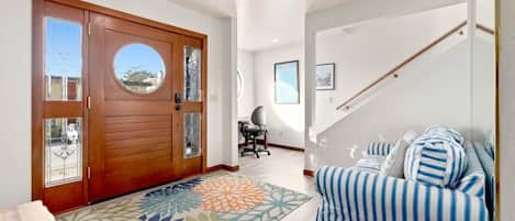 A modern living room with a sofa, a patterned rug, and a wooden door with glass panels.