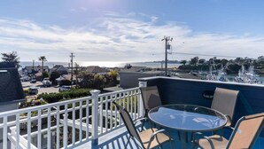 A balcony with a table and chairs overlooking a marina with boats.