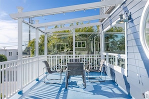 A covered outdoor area with a glass enclosure, white railings, and a seating arrangement. - Harbor Home - 2 blocks from the beach! (Santa Cruz)