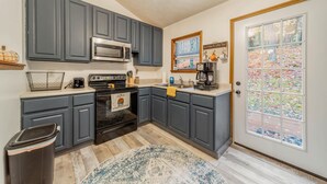A kitchen with grey cabinets, a microwave, an oven, and a coffee maker. - Private Lake/Beach Cabin w/Golf, Pool, Fire pit (Terra Alta)