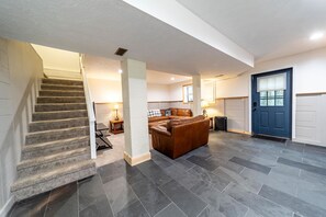 Un vaste espace de vie comprenant un escalier, une porte bleue et un canapé en cuir.