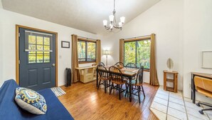 A room with a bed, a dining table with chairs, a small table with a lamp, and a window with curtains. - Private Lake/Beach Cabin w/Golf, Pool, Fire pit (Terra Alta)