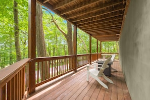 Eine Holzterrasse mit Geländer, weißen Stühlen und einem Tisch.