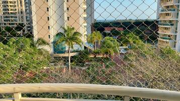 A chain-link fence with a view of tall buildings and a street with cars.