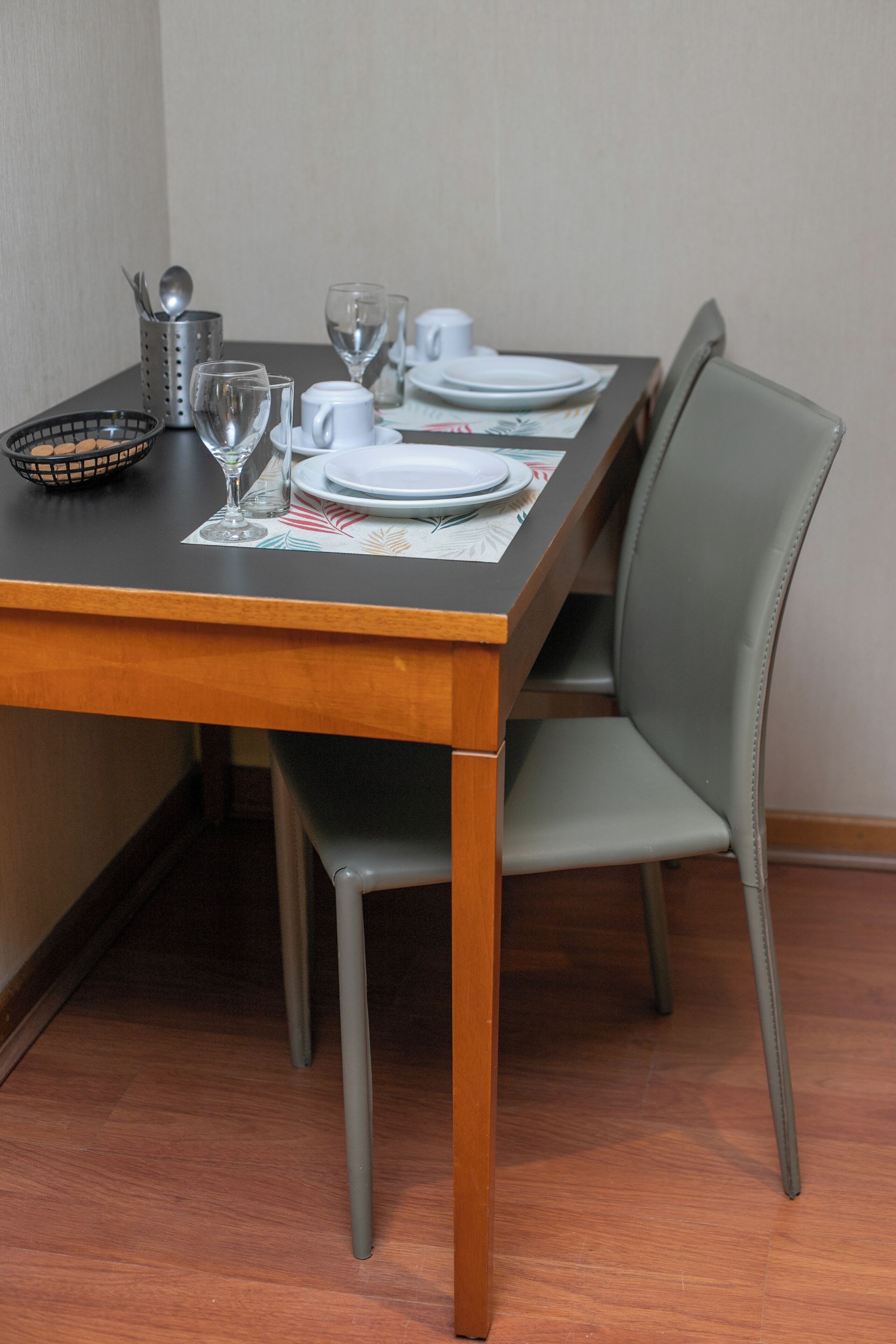 Una mesa de comedor dispuesta con platos, vasos y un tazón.