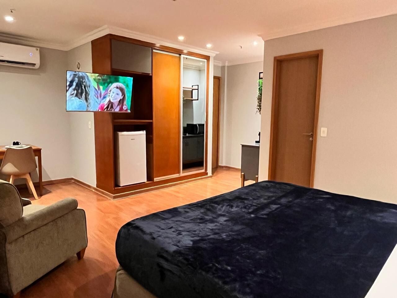 A bedroom with a bed, a TV, a desk, and a wardrobe.