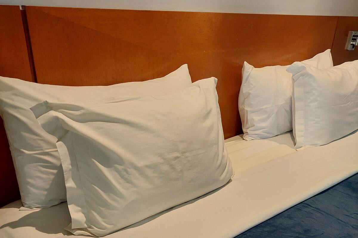 A bed with white pillows and a blue bedspread.