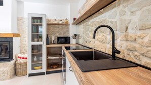 A modern kitchen with a stone wall, a black sink, and a microwave.