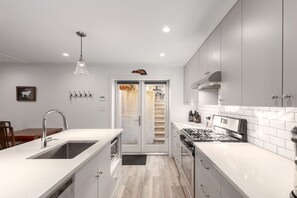 A modern kitchen with white cabinetry, a stainless steel sink, and a built-in stove.