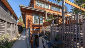 Il s’agit d’une propriété résidentielle dotée d’une terrasse en bois, d’un petit espace extérieur aménagé avec des chaises et une table, et d’une clôture en bois.
