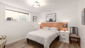 Une chambre à coucher moderne avec un lit, des tables de chevet, une chaise et une fenêtre.