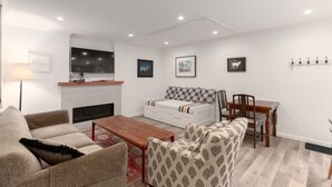 Un salon moderne avec une cheminée, un canapé, un fauteuil et une table à manger.