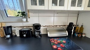 A kitchen with a coffee maker, toaster, and a cutting board with a tomato design. - Refugium 2020 - The vacation apartment - 69 sqm with balcony, perfect for 4 people, max. 7 (Marienheide)