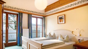 Una camera da letto con un letto, una finestra con tende, un termosifone e un quadro appeso al muro.