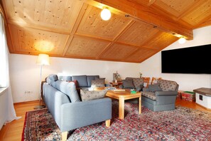 Ein Wohnzimmer mit Holzboden, einer Couch, einem Couchtisch und einem gemusterten Teppich.