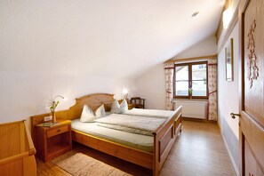 Ein Schlafzimmer mit einem hölzernen Bett, Nachttischen, einem Vorhangfenster und einer Heizung.