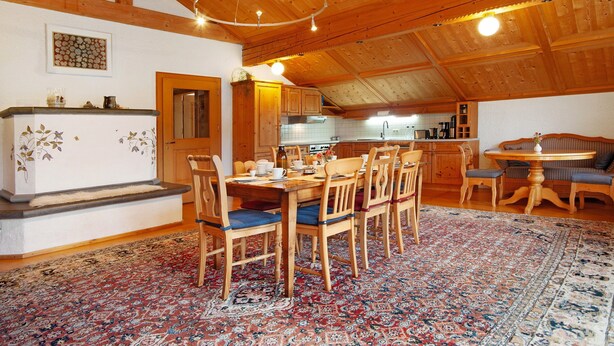 Un interno in legno con zona pranzo, cucina e un tavolo rotondo con sedie.