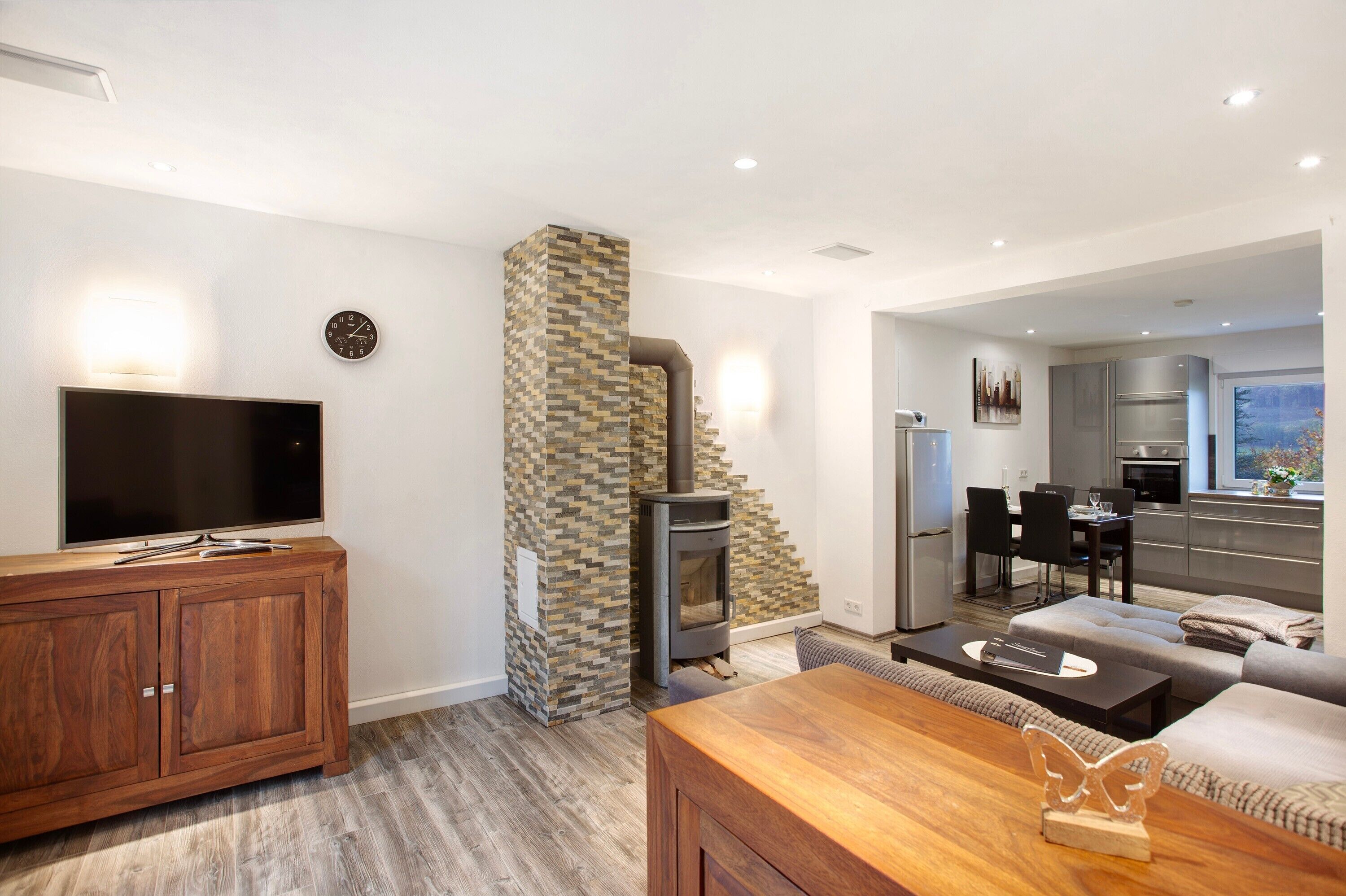 Un salon moderne avec un téléviseur, un meuble en bois et une cheminée.