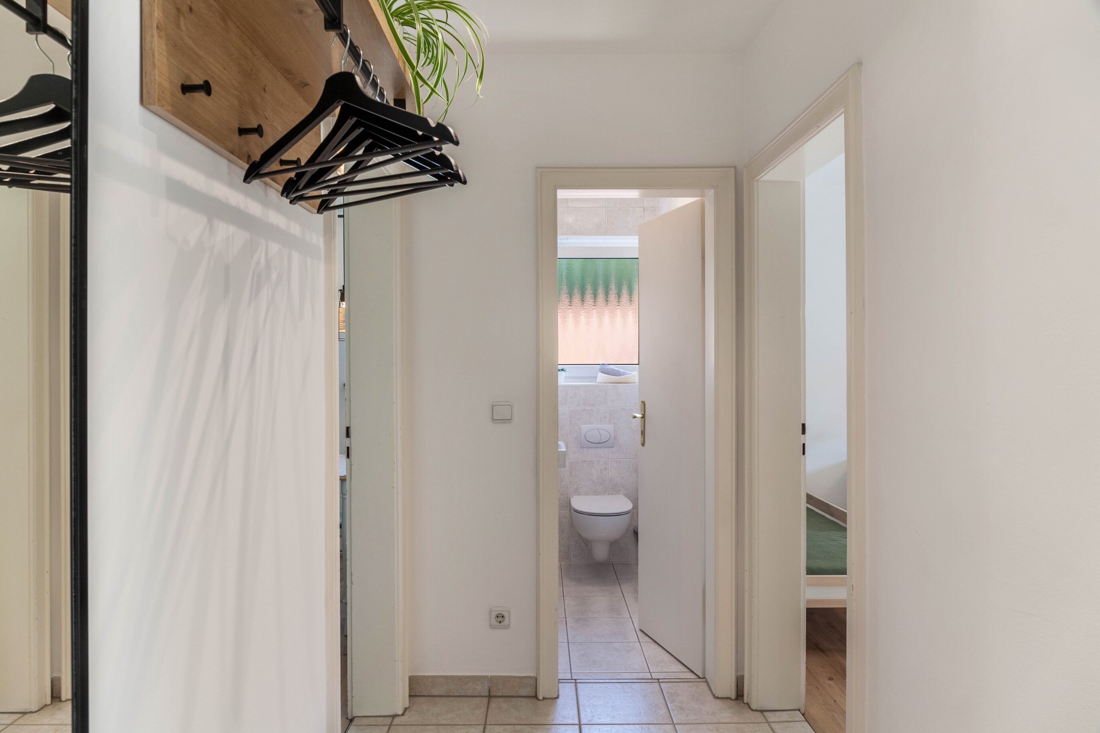 Un pasillo estrecho con una puerta de madera que da a un baño.