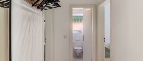 Un pasillo estrecho con una puerta de madera que da a un baño.