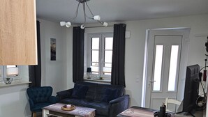 Un ambiente compatto con angolo cottura, divano, tavolo da pranzo e televisione.