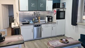Una cucina compatta con elettrodomestici moderni, una zona pranzo con tavolo e sedie, e un'accogliente area salotto con divano.