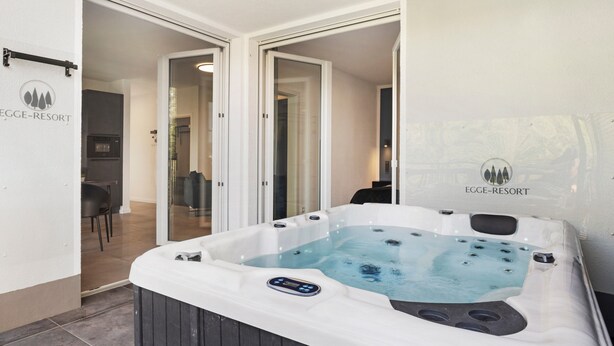 Ein Whirlpool mit Bedienfeld, ein Essbereich mit Stühlen und eine Küchenzeile inklusive Kühlschrank.