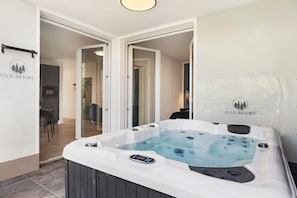 A hot tub with a control panel, a dining area with chairs, and a kitchen area with a refrigerator. - Apartment "Egge Resort 7e" with Balcony, Whirlpool & Sauna (Altenbeken)