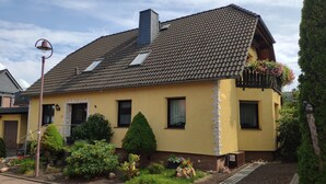 A yellow house with a tiled roof, a chimney, and a small garden with various plants and a cactus. - Apartment 'Mone's Kloetze' with Private Terrace, Wi-Fi and Air Conditioning (Klötze)