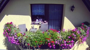 A balcony with wicker furniture, a table, and a window with curtains. - Apartment 'Mone's Kloetze' with Private Terrace, Wi-Fi and Air Conditioning (Klötze)