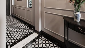 A hallway with a patterned floor, a framed painting, and a vase with flowers on a console table. - Dai Thuy Hotel (Hai Phong)