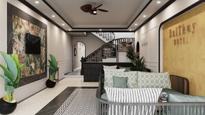 A modern hotel lobby with a staircase, a reception desk, and a seating area. - Dai Thuy Hotel (Hai Phong)