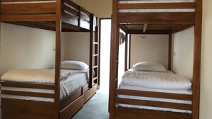 Two bunk beds with wooden frames and white bedding, a ladder, and a door leading to another room. - Roots Hotel Trawangan (Gili Trawangan)
