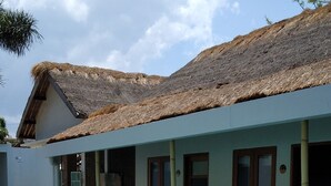 A swimming pool with a wooden deck, a building with a thatched roof, and a clear sky. - Roots Hotel Trawangan (Gili Trawangan)