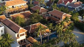 A residential area with multiple houses, a swimming pool, and palm trees. - Su Retreat Hoi An - Riverfront Resort (Da Nang)